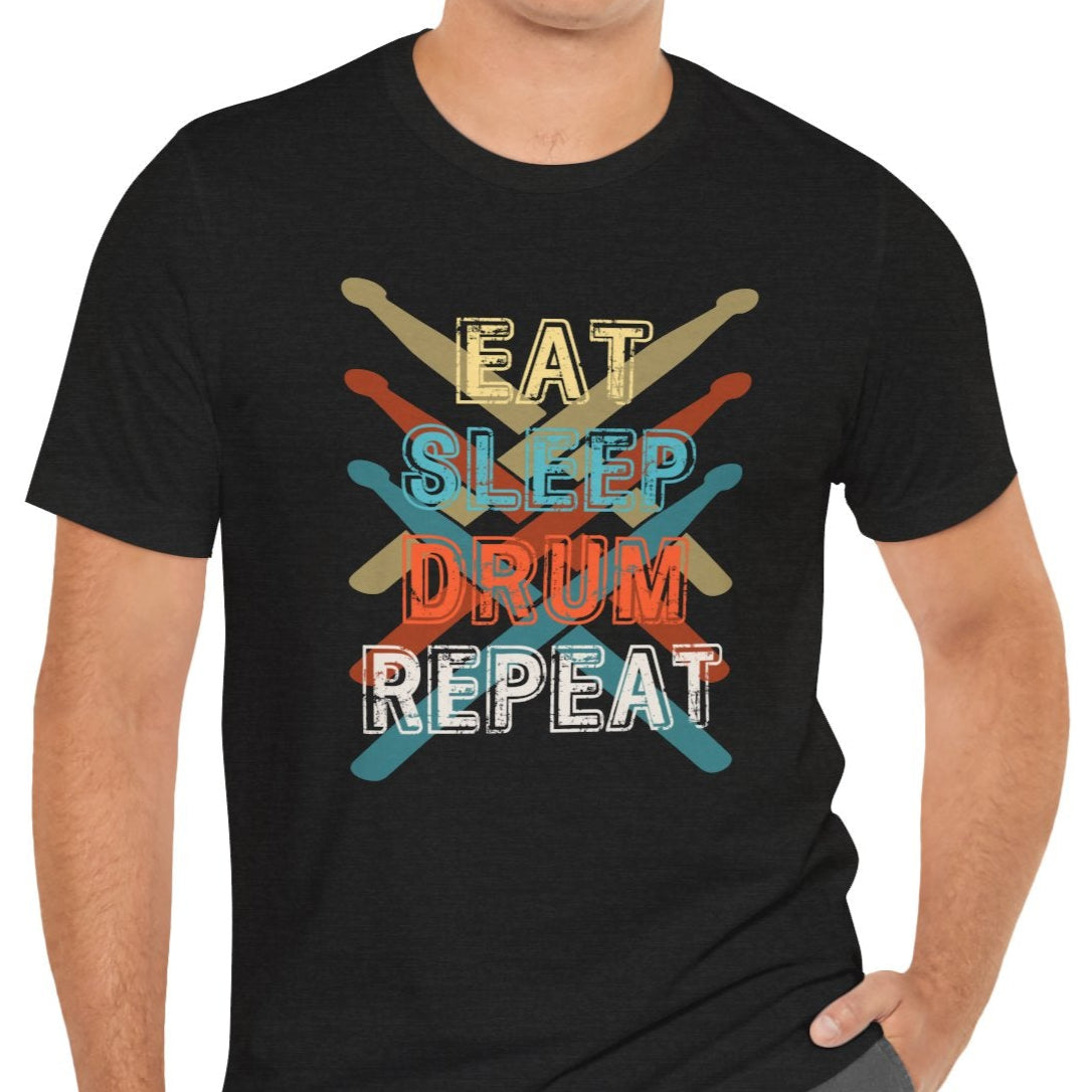 A person wearing a black t-shirt with the text 'EAT, SLEEP, DRUM, REPEAT' written in a repeating pattern with different colors for each word.