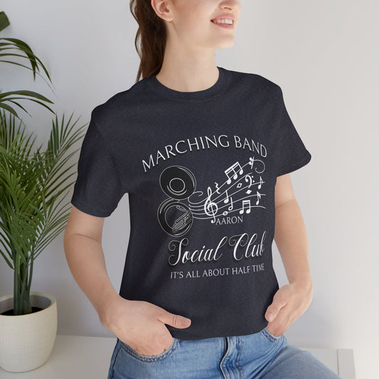 Person wearing a black t-shirt with 'Marching Band & Social Club' design, standing indoors.