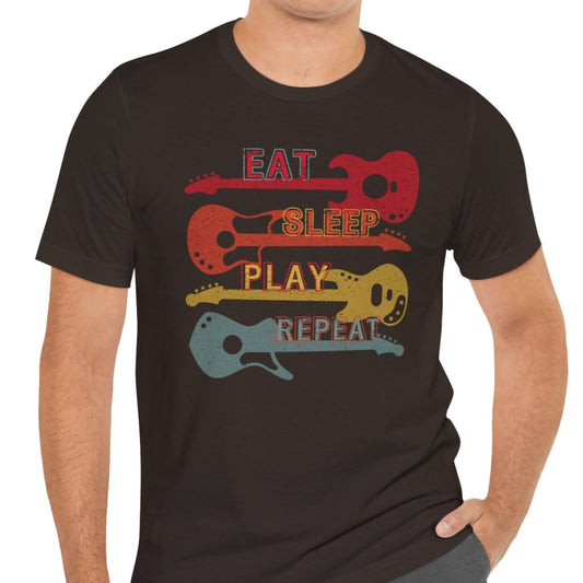 A person wearing a black t-shirt with a text graphic that reads 'EAT SLEEP PLAY REPEAT' and a graphic of a guitar. The shirt is crew-necked and made of cotton.