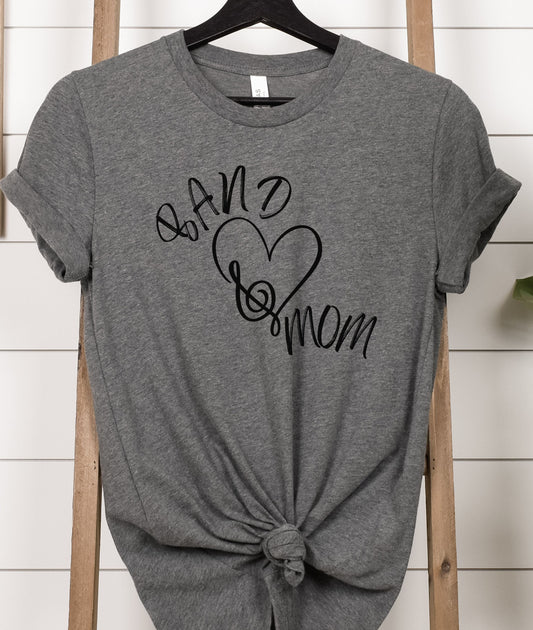 A gray marching band mom t-shirt displayed on a wooden hanger, featuring text and a heart graphic on the front.