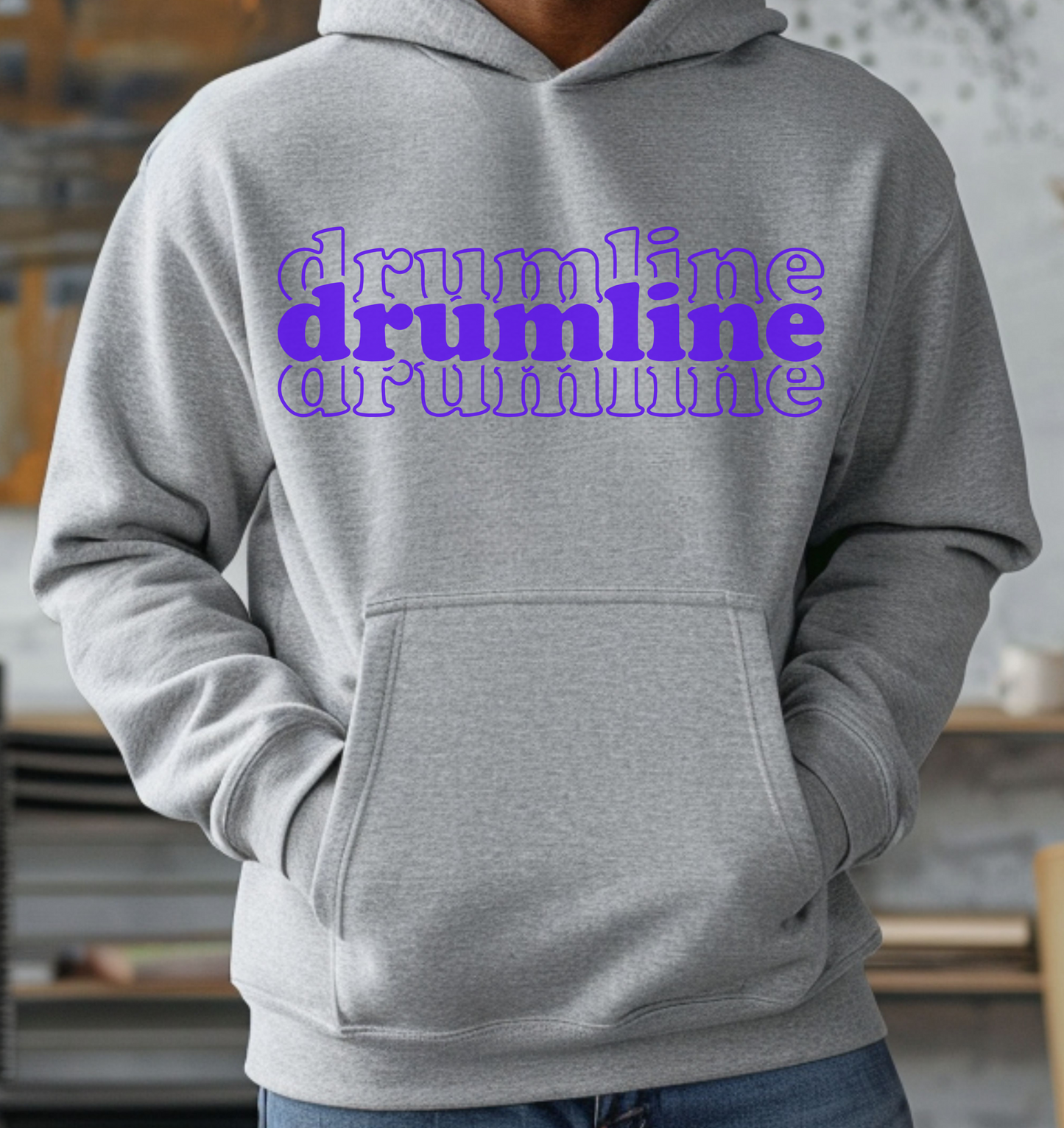A person wearing a gray hoodie with the text 'Drumline Marching Band' printed in white on the front.